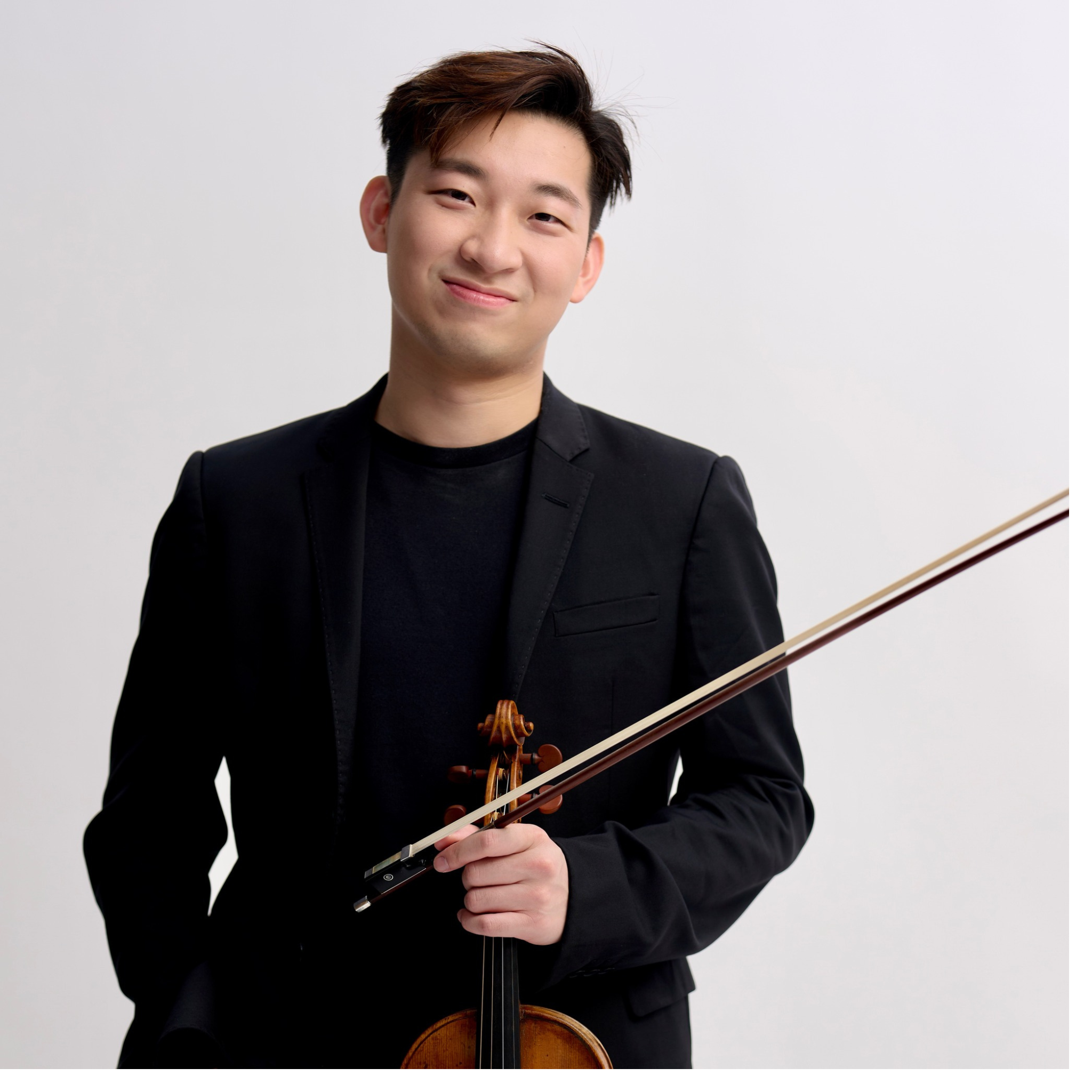 Hiu Sing Fan poses in front of a white background with his violin.